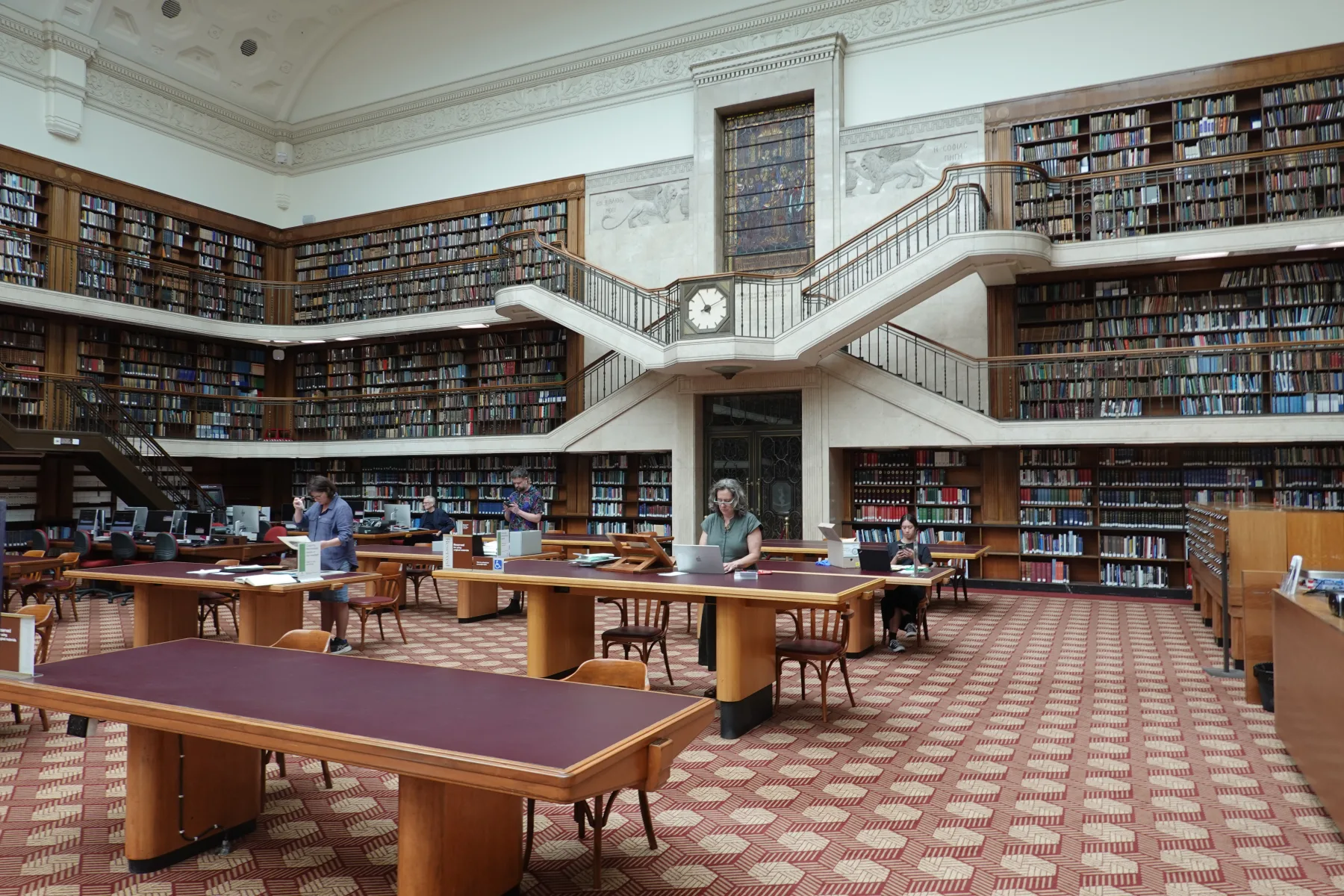 時計を挟んだ左右の階段と木製書架が見えるミッチェル図書館閲覧室
