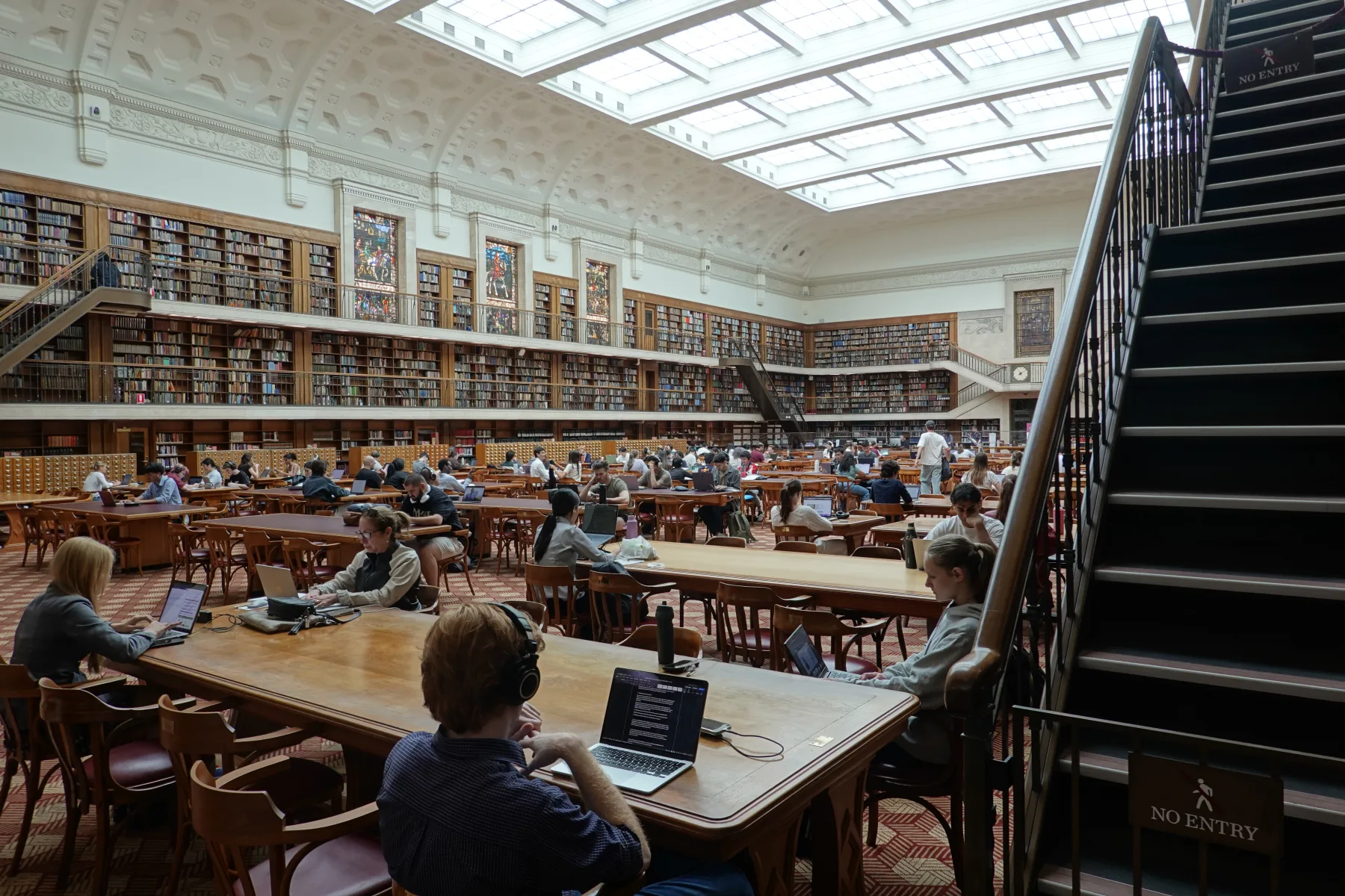 長い机と緑色の読書灯が並ぶミッチェル図書館閲覧室