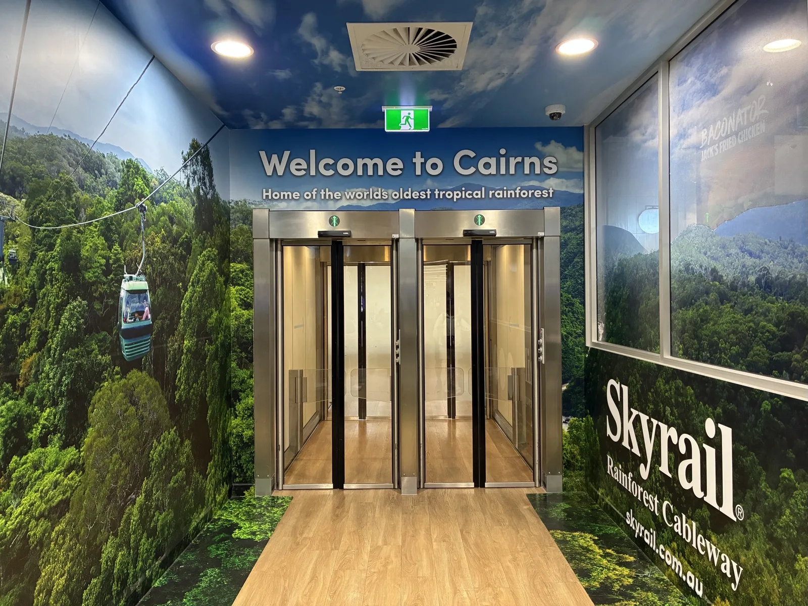 ケアンズ空港に飾られたWelcome to Cairnsの案内とスカイレールのゴンドラ
