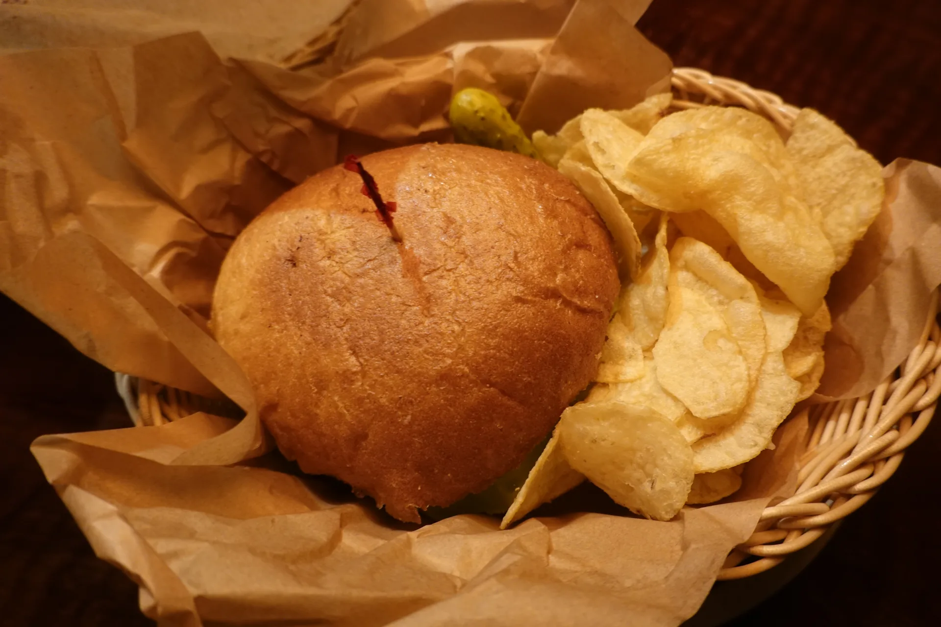 丸いパンとポテトチップスを籠に盛ったザ・イエロー・デリのサンドイッチ